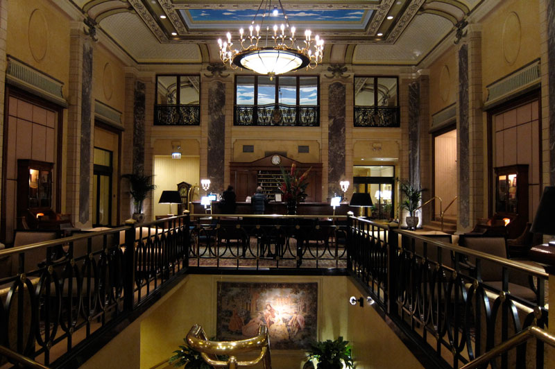 The lobby of the Belden-Stratford is ornamented with columns, pilasters, iron-work, and a beautiful hanging light.